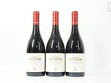 trois bouteilles de vin rouge posées l'une à côté de l'autre sur une surface blanche