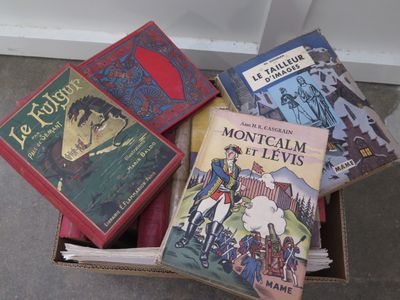 several books in a box sitting on the floor in front of a wall