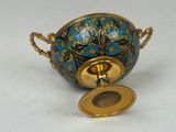 a blue and gold vase with a gold lid on a white surface