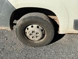 une camionnette blanche avec un pneu crevé, garée sur le bord de la route