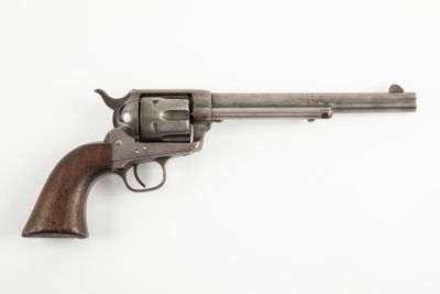 un vieux revolver avec un manche en bois sur fond blanc