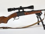 le fusil est posé sur un support et est équipé d'une lunette de visée