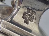 a close up of a silver vase with a bird on it