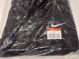 une chemise noire emballée dans du plastique, posée sur une surface blanche