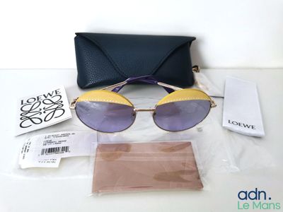 des lunettes de soleil violettes et dorées et un étui noir posés sur une table blanche