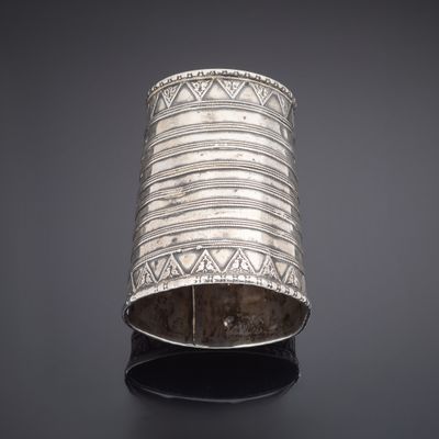 a silver cuff bracelet with geometric designs on a black surface
