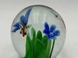 a glass paperweight with blue flowers inside of it
