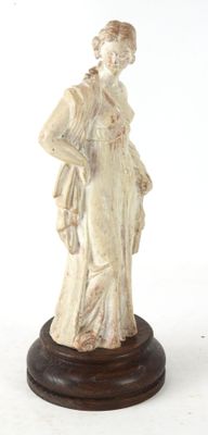 statue d'une femme en robe blanche posée sur un socle en bois