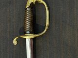a sword with a gold handle on a black surface