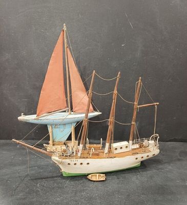 une petite maquette de voilier avec une voile rouge