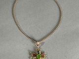 collier plaqué or avec un pendentif en forme de croix et une perle verte et rouge