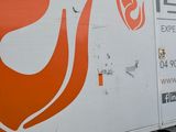 an orange and white truck parked in a parking lot next to a building