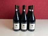 three bottles of wine sit on a table in front of a red wall