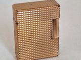 un petit briquet doré posé sur une surface blanche