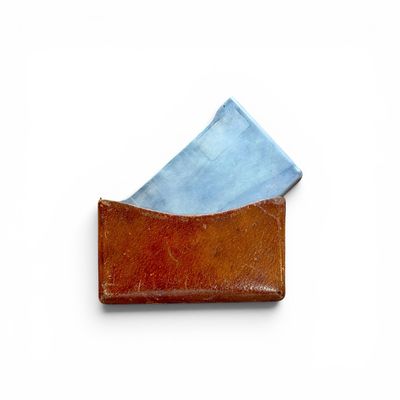 leather business card holder with blue paper in it on a white surface