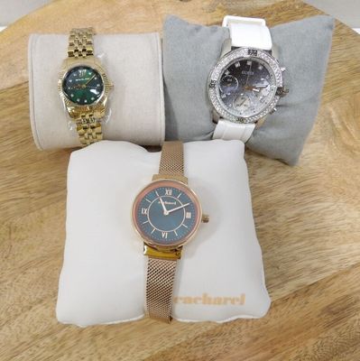 three watches are sitting on a pillow on a wooden table
