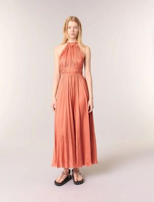the woman in the dress is posing for the camera with her hands in her pockets