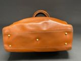 an image of a brown leather bag with rivets and rivets on the handles