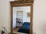 un miroir posé sur une commode, avec un lit bleu en arrière-plan