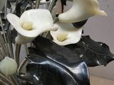 un vase noir avec des fleurs blanches à l'intérieur, posé sur une table