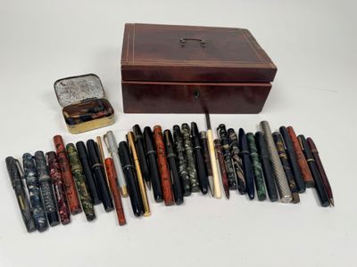 un assortiment de stylos et une boîte posés sur une surface blanche