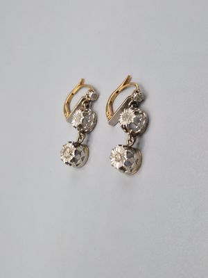 a pair of gold and diamond earrings on a white surface