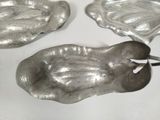 two silver dishes on a white table with a pair of scissors