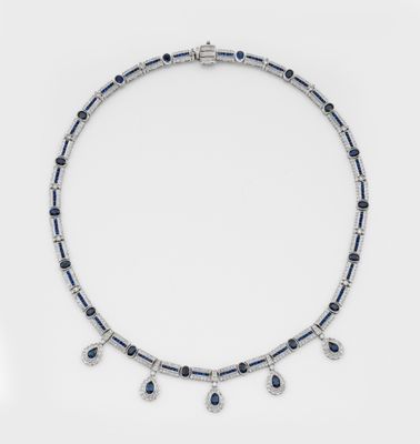 un gros plan d'un collier orné de pierres bleues et blanches sur un fond blanc
