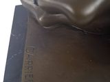a bronze statue of a foot that is on top of a book