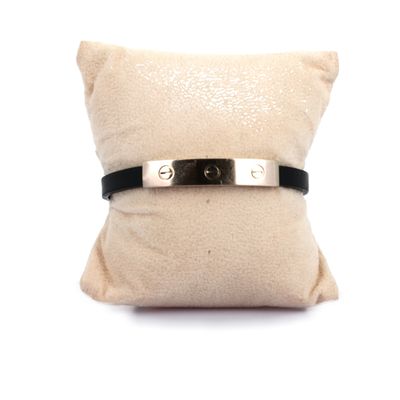 bracelet en cuir noir avec un fermoir en argent posé sur un coussin blanc