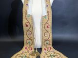 un mannequin blanc orné de franges dorées et de perles colorées