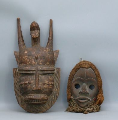 two wooden masks are sitting next to each other on a white surface