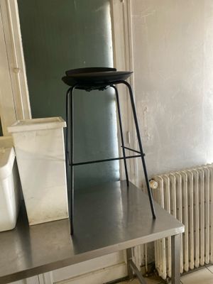 une table en métal sur laquelle est posé un tabouret, dans une pièce