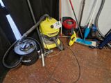 a yellow vacuum sitting on the floor next to other vacuums