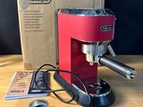 a red coffee machine sitting on a table next to a box