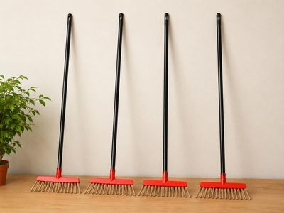 trois balais et une plante en pot posés sur une table en bois