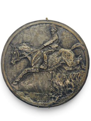 une plaque métallique sur laquelle figurent un cheval et son cavalier