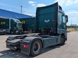 a green semi truck that is parked in front of a building