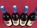 four bottles of wine are lined up on a red surface