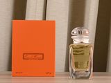 une boîte orange posée sur une table, à côté d'un flacon de parfum
