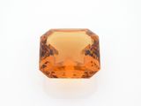 a close up of an orange sapphire stone on a white surface