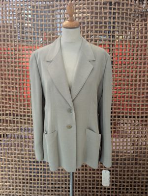 a suit on a mannequin stand in front of a woven wall