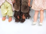 three dolls standing next to each other on a white surface