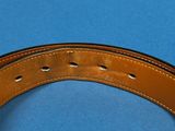 brown leather belt on a blue surface with holes in the center