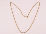 un collier à chaîne en or orné d'une boule sur fond blanc