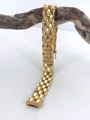 gold plated bracelet on a branch on a white background