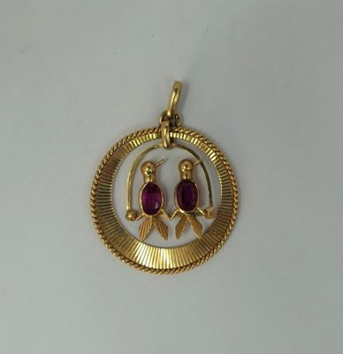 a close up of a gold plated pendant with two birds on it