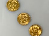 Trois pièces d'or sont représentées sur une surface blanche, sur fond blanc.