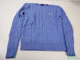 un gros plan d'un pull bleu posé sur une table blanche