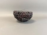 a close up of a beaded bowl on a white surface